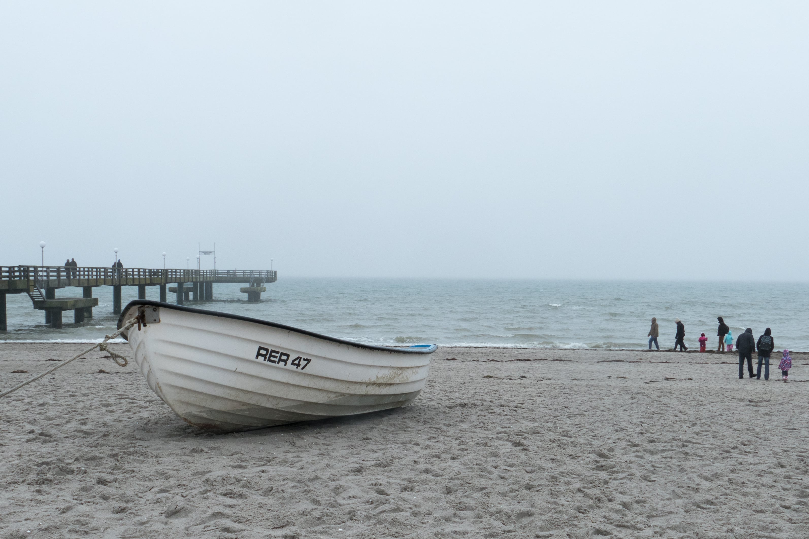 Holzboot am Stand im Vordergrund mit Menschen im Hintergrund und Steg aufgenommen mit Lumix Kamera